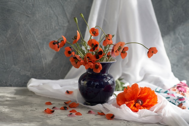 Un petit bouquet de coquelicots rouges dans un vase en céramique bleu