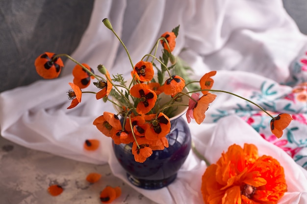 Un petit bouquet de coquelicots rouges dans un vase en céramique bleue