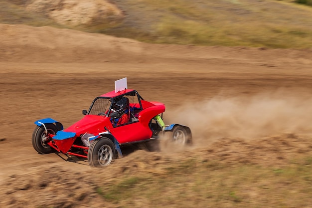 Un petit buggy sportif flou sur une piste de compétition de rallye pendant l'entraînement du week-end par une chaude journée d'été