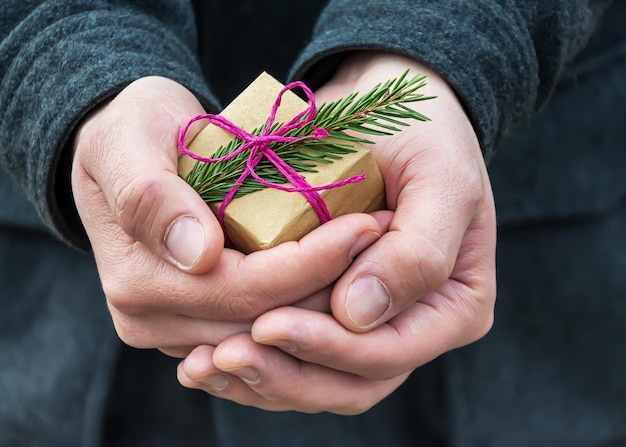 Un petit cadeau de Noël dans la main d'un jeune homme, mise au point sélective.