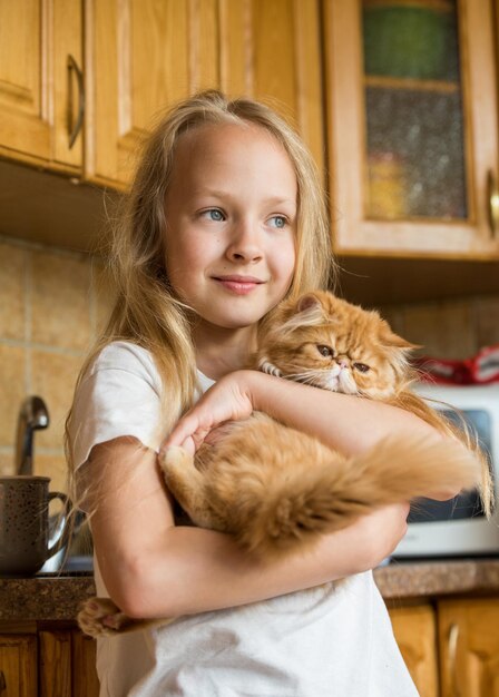 Petit chaton domestique persan mignon dans la main de la fille. Chat et enfant à la maison