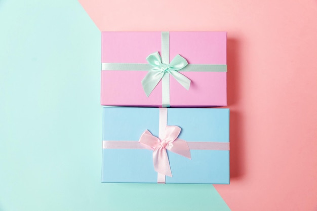 Petit coffret cadeau enveloppé de papier rose et bleu isolé sur fond géométrique tendance coloré pastel bleu et rose Noël Nouvel An anniversaire Saint Valentin célébration présent concept romantique