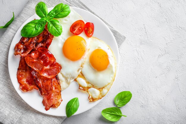 Petit-déjeuner américain complet avec des œufs au plat et du bacon rôti sur blanc.