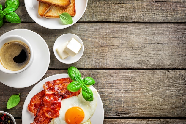 Petit-déjeuner américain complet avec des œufs au plat et du bacon rôti sur bois