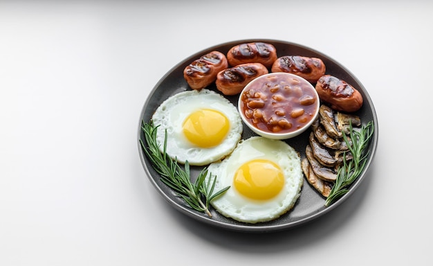 Petit-déjeuner anglais complet haricots œufs frits saucisses rôties tomates champignons sur une table en béton foncé avec du pain grillé