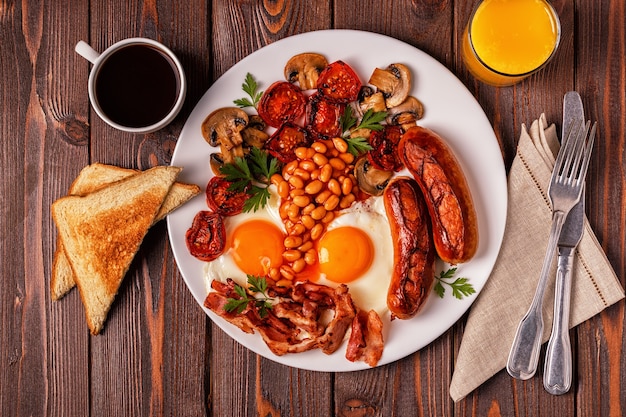 Petit-déjeuner anglais complet traditionnel avec des œufs au plat, des saucisses, des haricots, des champignons