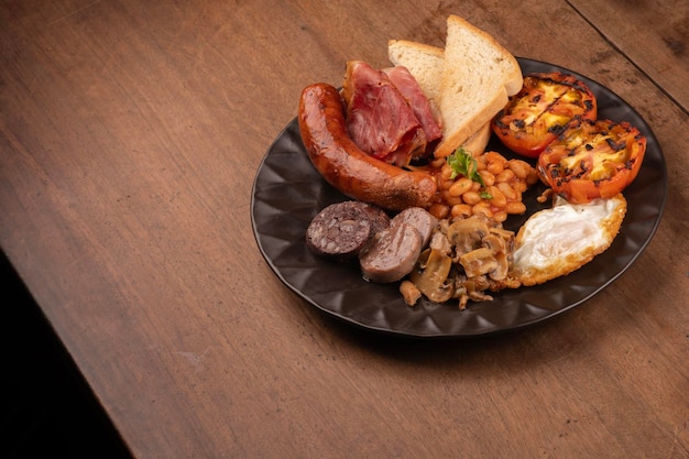 petit déjeuner anglais irlandais britannique avec beaucoup de protéines haricots sucrés saucisses bacon œufs champignons table en bois de près