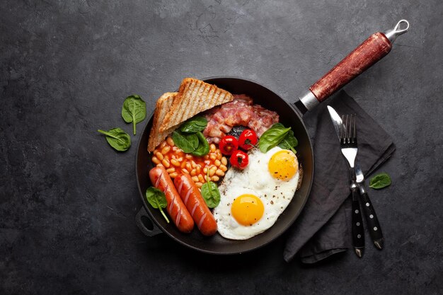 Petit-déjeuner anglais avec des œufs au plat, des haricots, du bacon et des saucisses