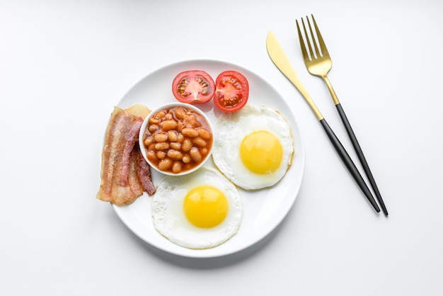 Petit-déjeuner anglais avec œufs frits bacon haricots tomates épices et herbes