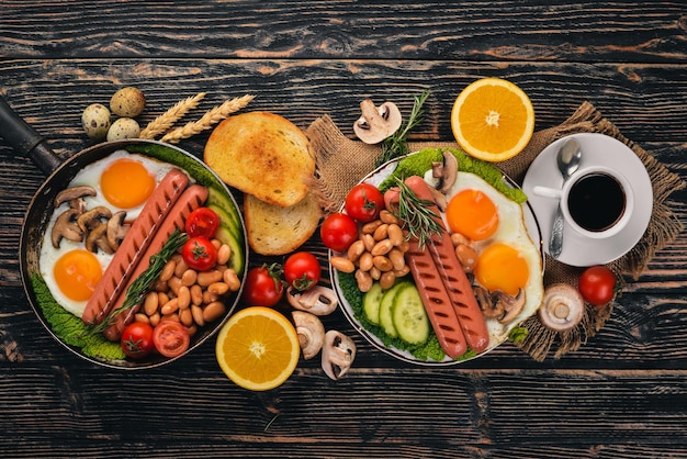 Petit-déjeuner anglais œufs frits haricots tomates champignons bacon et toast Vue de dessus sur un fond en bois