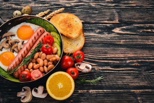 Petit-déjeuner anglais œufs frits haricots tomates champignons bacon et toast Vue de dessus sur un fond en bois