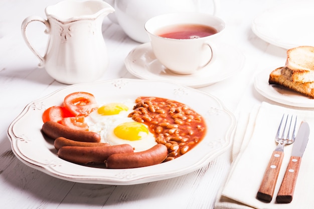 Petit-déjeuner anglais - œufs, saucisses aux haricots et thé au lait