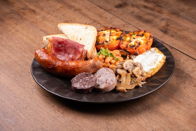 petit déjeuner appétissant anglais irlandais britannique avec beaucoup de protéines haricots douces saucisses bacon œufs champignons table en bois de près