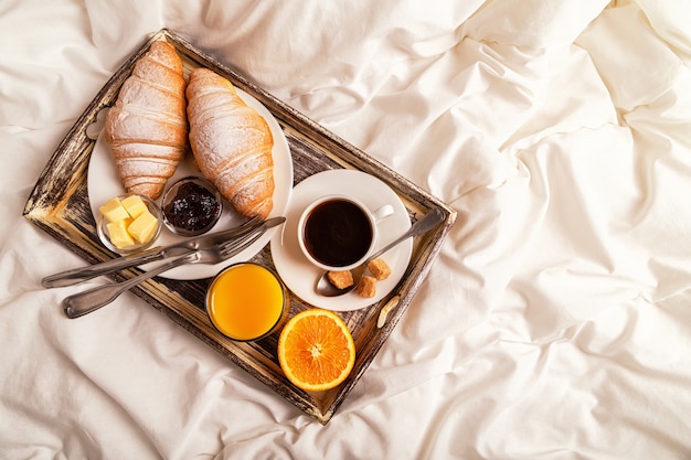 Petit déjeuner au lit avec café et croissants