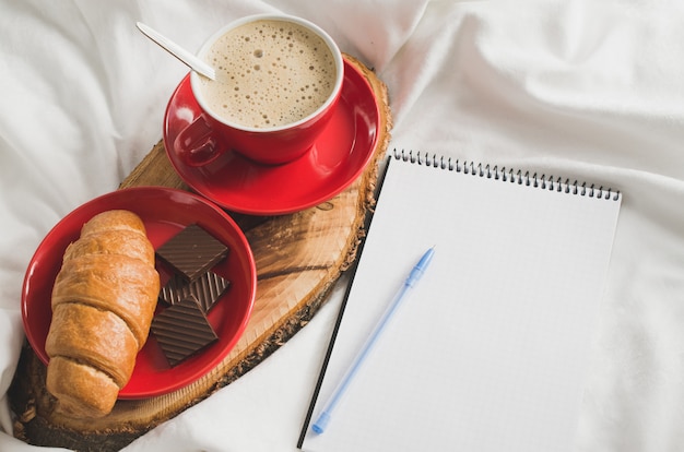 Petit déjeuner au lit et cahier vide pour la note.