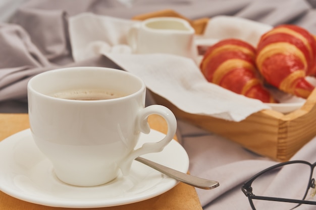 Petit-déjeuner au lit avec expresso, fleur et croissant