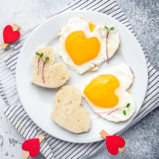 Petit-déjeuner aux œufs de saint valentin sur la table des œufs frits brouillés en forme de coeur décoration de vacances d'amour