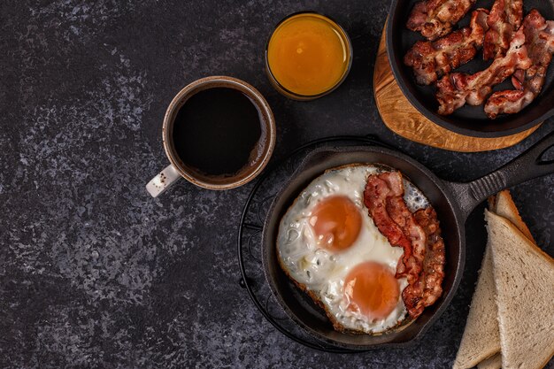 Petit-déjeuner avec bacon, œuf au plat, café et jus d'orange