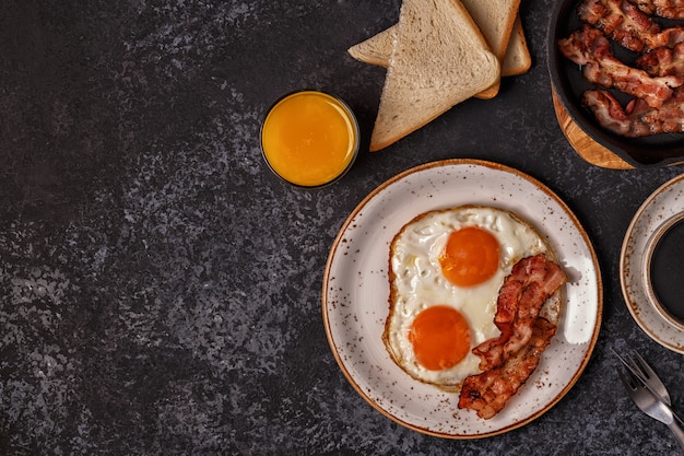 Petit-déjeuner avec bacon, œuf au plat, café et jus d'orange