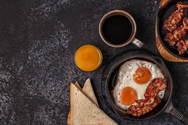 Petit-déjeuner avec bacon, œuf au plat, café et jus d'orange