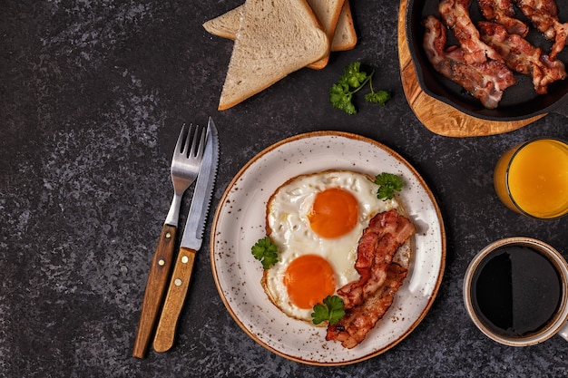 Petit-déjeuner avec bacon, œuf au plat, café et jus d'orange