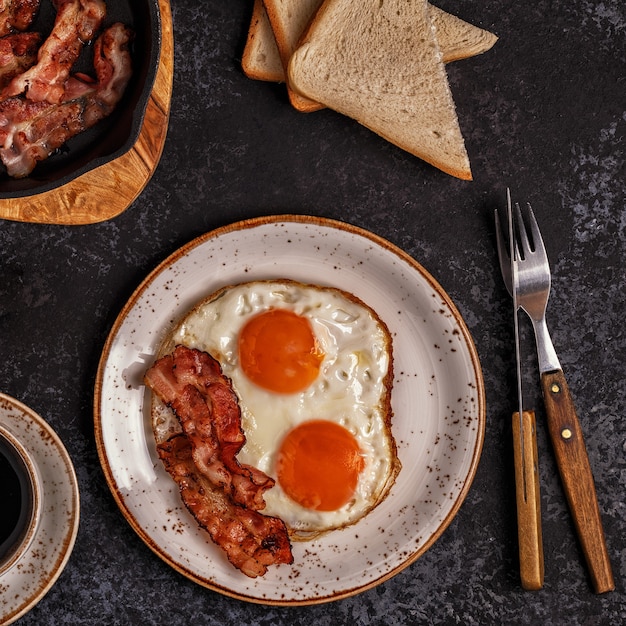 Petit-déjeuner avec bacon, œuf au plat, café et jus d'orange