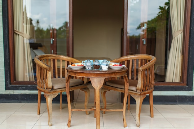 Petit déjeuner balinesse traditionnel avec deux tasses bleues de boisson chaude sur une table en bois.