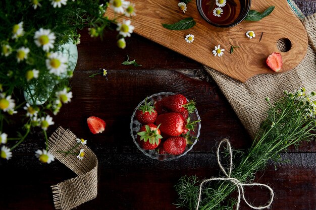 Petit-déjeuner bio naturel Fraises fraîches fleurs de camomille d'été tisane et menthe sur table en bois Style de vie estival atmosphérique Belle nourriture Connexion avec la nature Espace de copie