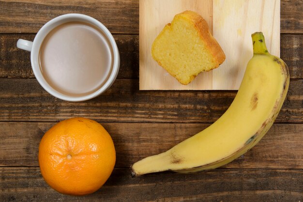 Petit-déjeuner brésilien avec café au lait, gâteau de maïs, banane et mandarine