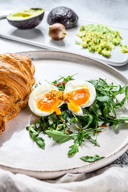 Petit déjeuner, brunch avec avocat, roquette, croissant et œuf.