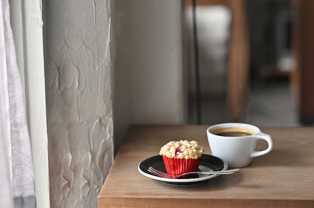 Petit déjeuner avec café noir et muffins faits maison sur une table en bois.