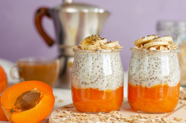 Petit déjeuner avec café, plats d'avoine, pudding aux graines de chia et fruits sur une planche de bois.