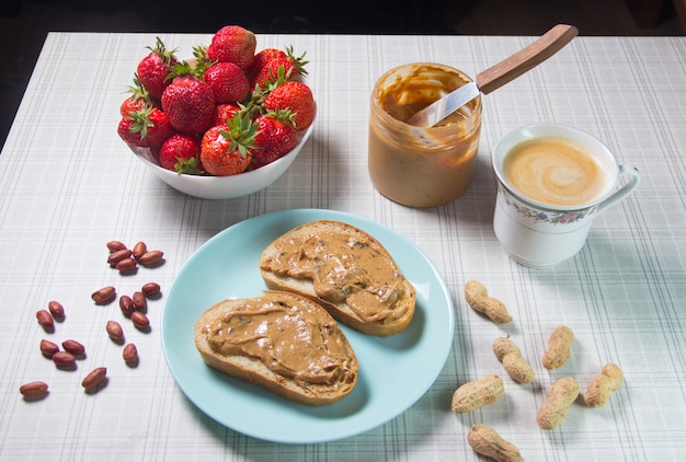 Petit déjeuner avec café et sandwichs avec pâte d'arachide et fraises