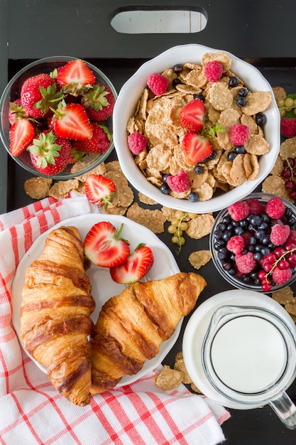 Petit déjeuner - céréales et baies dans un bol blanc, croissant