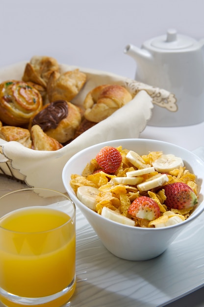 Photo petit déjeuner avec des céréales avec des fruits, du jus et des pâtisseries.