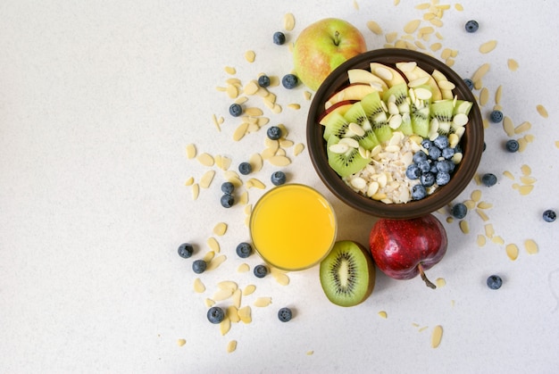 Petit-déjeuner ou collation santé d'été. Flocons d'avoine avec des baies et des fruits, du jus et du krassan sur une table plate blanche