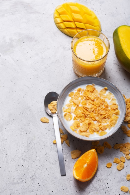 Petit déjeuner composé de différents ingrédients jaunes - sereales et fruits. Fond gris