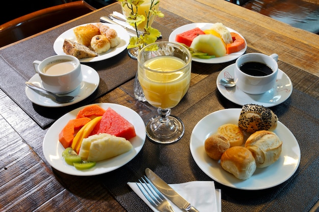 Petit déjeuner composé de fruits, jus d'orange, café, pain.