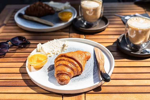 Petit-déjeuner avec confiture d'orange croissant croustillant frais et beurre avec cappuccino Matin ensoleillé