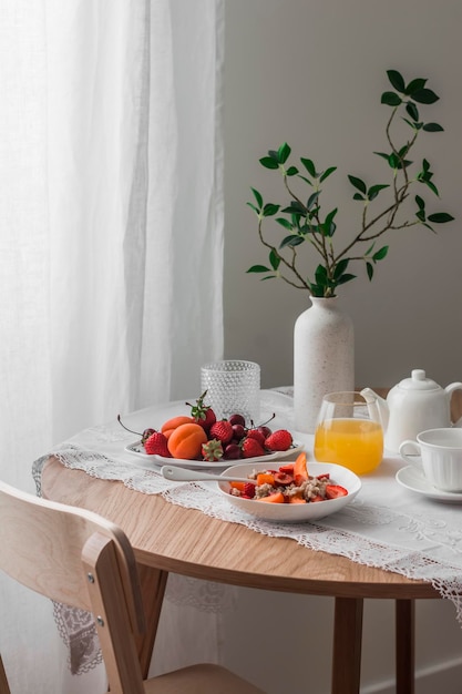 Petit-déjeuner confortable servi de la bouillie d'avoine avec des fruits de saison et des baies de thé au jus d'orange sur une table ronde en bois