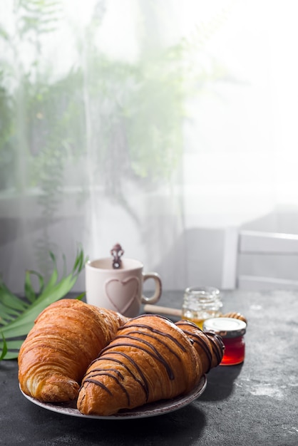 Petit déjeuner continental croissant fraîchement sorti du four, décoré avec de la confiture et du chocolat