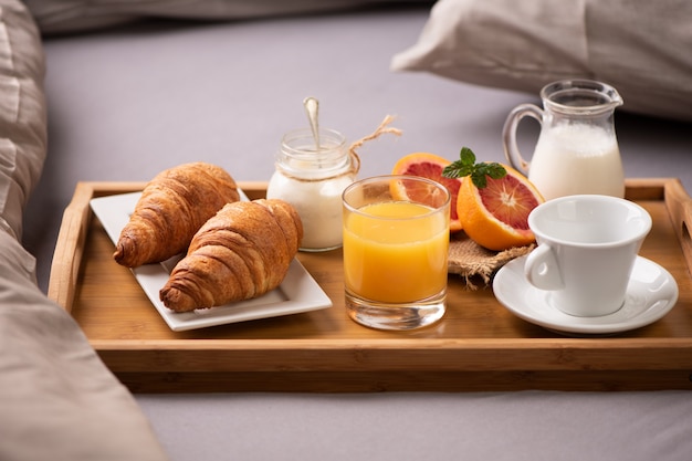 Petit Déjeuner Continental. Plateau De Petit-déjeuner Sur Lit Avec Café,  Jus D'orange Et Croissant Se Bouchent