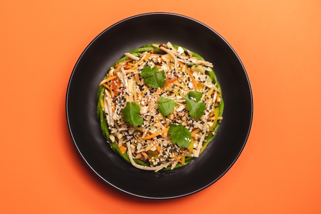 Petit-déjeuner copieux dans une assiette noire sur fond orange. Vue d'en-haut. Photographie culinaire