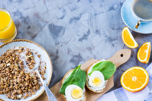 Petit déjeuner copieux et sain - muesli, sandwich à l&#39;oeuf, café, orange et jus