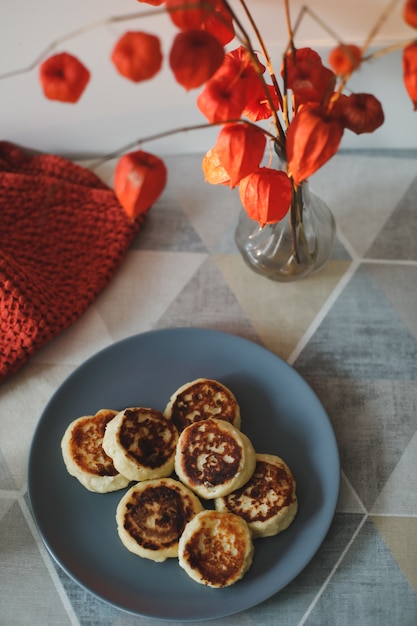 petit-déjeuner avec des crêpes au fromage cottage maison, une tasse de thé et des fleurs dans un vase sur la table