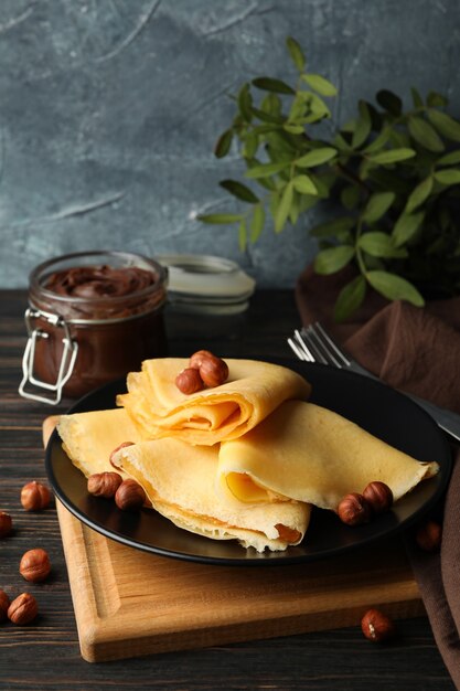 Petit-déjeuner avec crêpes avec pâte de chocolat et noix sur table en bois