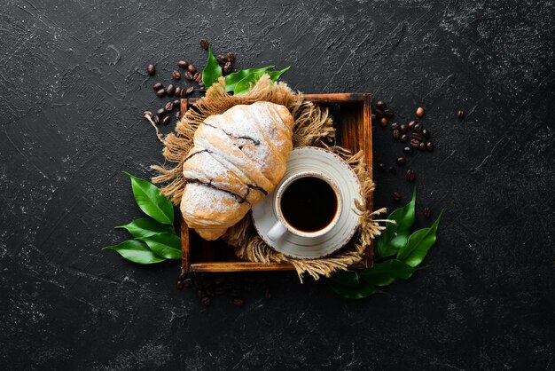 Petit-déjeuner Croissant au café et macarons Sur fond de pierre noire Vue de dessus Espace libre pour votre texte