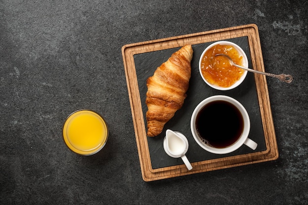 Petit déjeuner avec croissant, café, confiture d'orange et jus