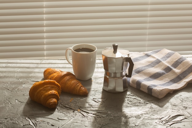 Petit déjeuner avec croissant et café et pot de moka. Concept de repas du matin et de petit-déjeuner.