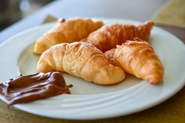 Photo petit-déjeuner croissant avec crème au chocolat sur une assiette.